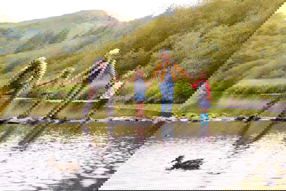 A family walking across stepping stones in a park.